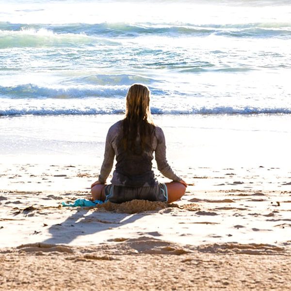 woman meditation next to ocean during meditation retreat in california